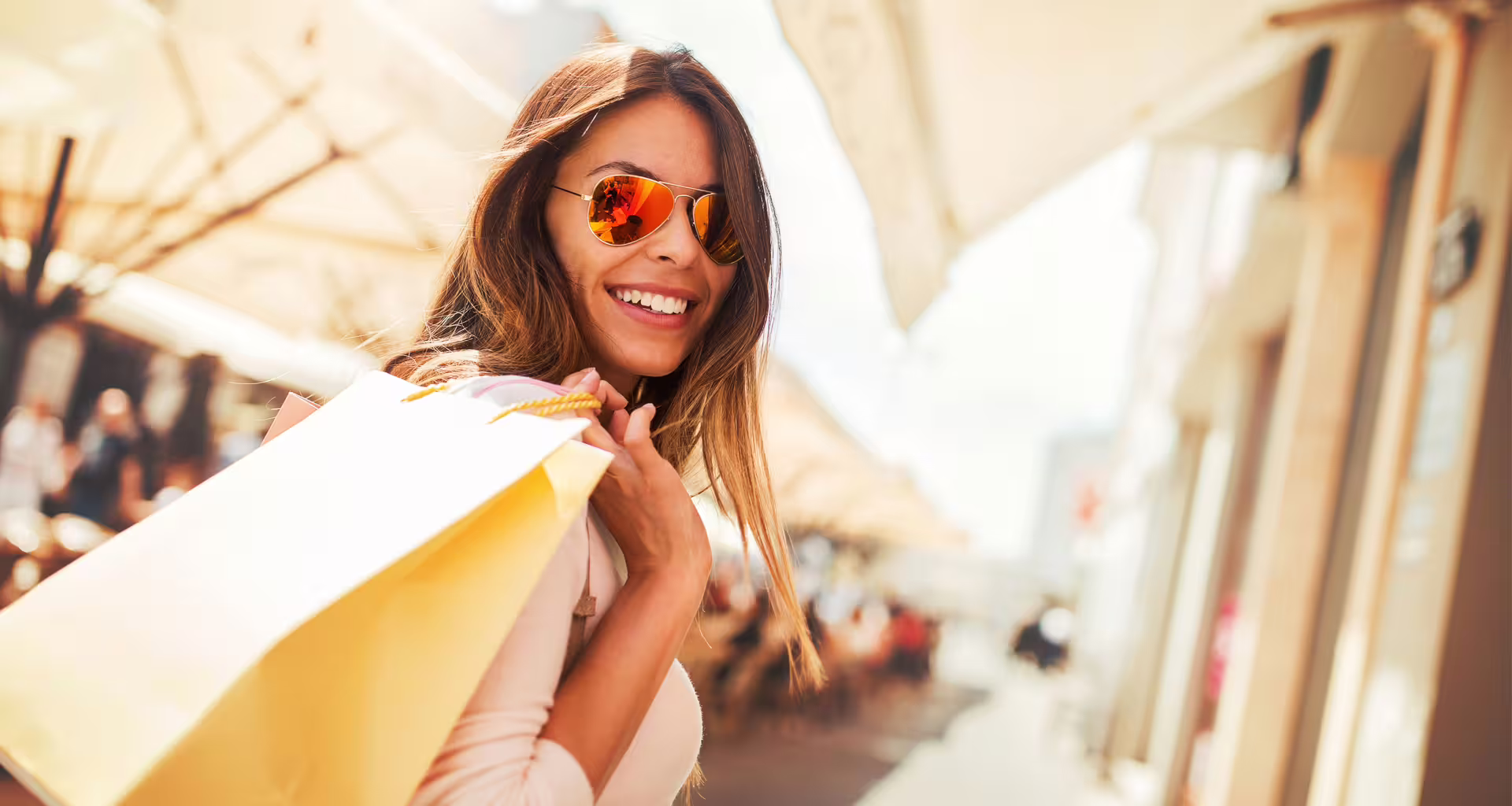 Happy shopper with sunglasses carries colorful bags at Designer Outlet La Reggia, enjoying an outdoor Naples shopping experience