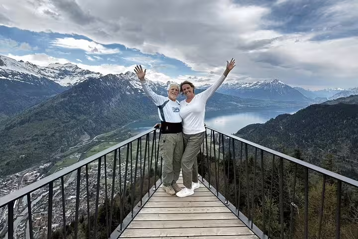 Tourists enjoying scenic views from the Harder Kulm viewpoint, overlooking Interlaken and the Swiss Alps.