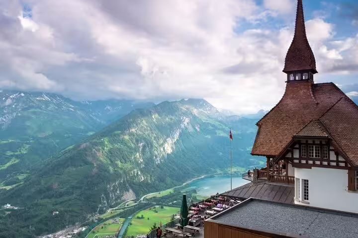 Panoramic view from Harder Kulm overlooking Swiss Alps and Lake Brienz with iconic wooden structure in the foreground.