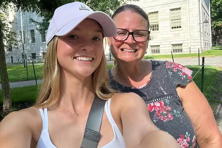 Two smiling women taking a selfie during the Harvard self-guided escape game and treasure hunt tour on a sunny day