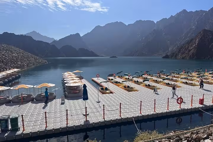 Floating dock at Hatta Dam with kayaks and pedal boats, mountain backdrop on private Hatta day trip from Dubai