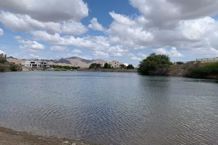 Hatta Dam lake view with desert mountains and clouds, scenic stop on private Hatta city tour from Dubai