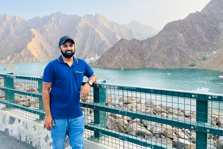Traveler at Hatta Dam viewpoint overlooking turquoise lake and Hajar Mountains on private full-day tour