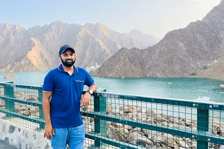 Traveler at Hatta Dam viewpoint with turquoise lake and rugged mountains, private full-day Hatta tour 1-6 pax