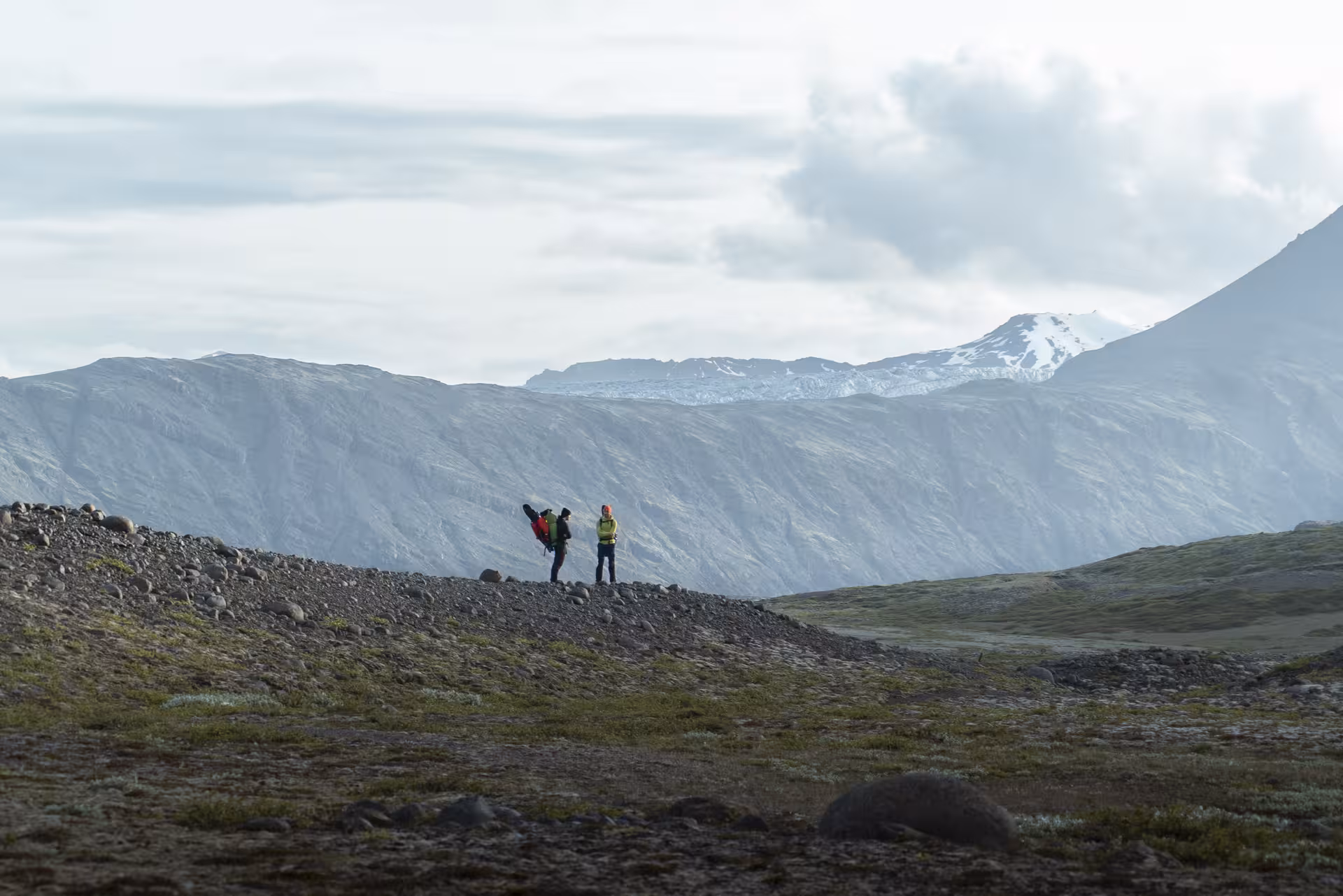 Hikers on a rocky ridge with glacier mountains on the Heinabergslón kayak and hike tour in Iceland