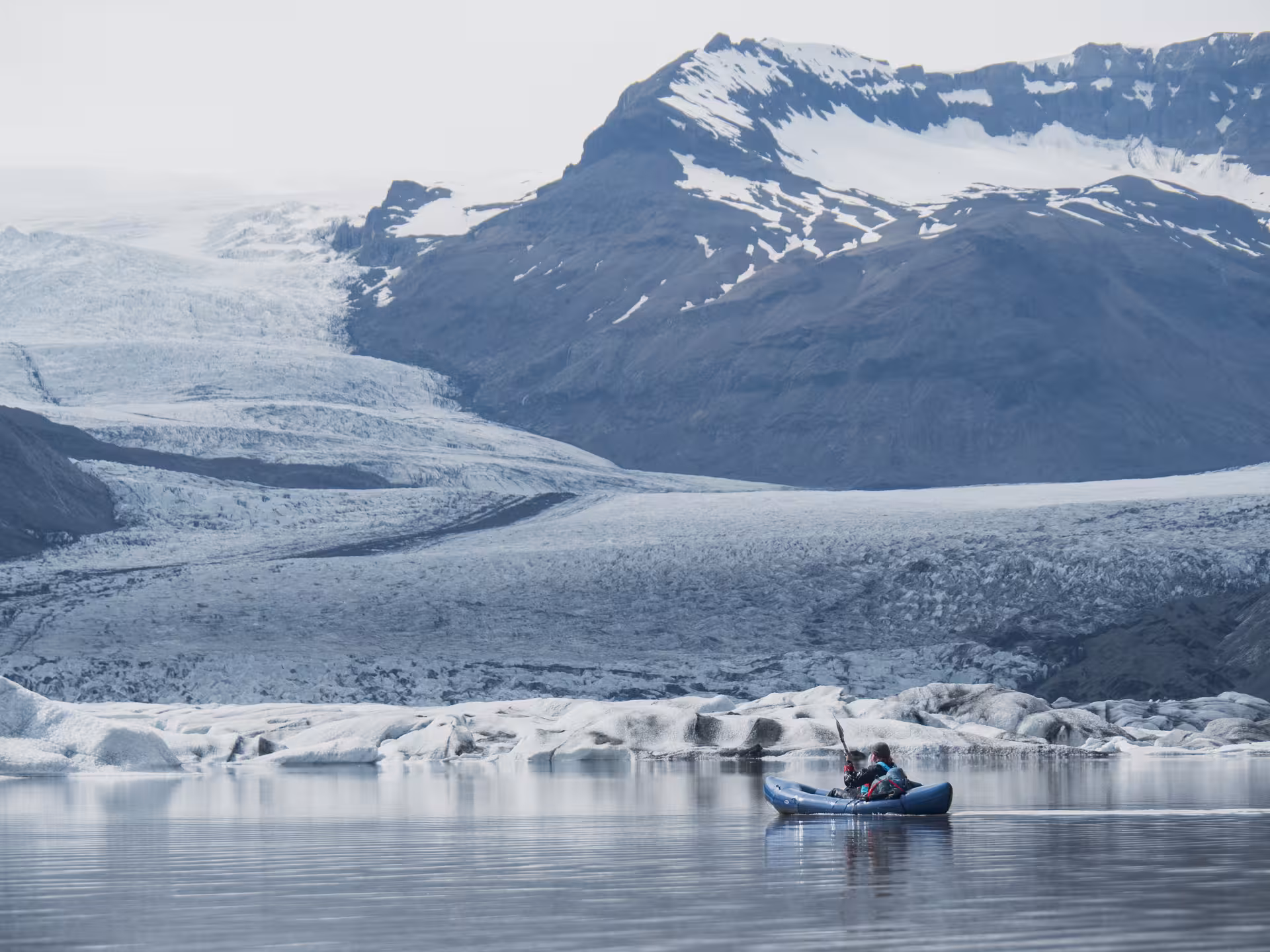 Kayakers paddle on Heinabergslón glacier lagoon with Vatnajökull ice and mountains on a kayak and hike tour