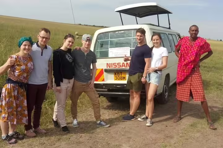 Group enjoying a safari at Hell's Gate with a safari van in the background, showcasing adventure and wildlife exploration.