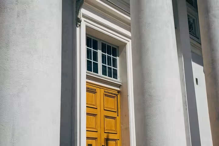 Close-up of a grand wooden door surrounded by neoclassical columns on a Helsinki architecture walking tour.