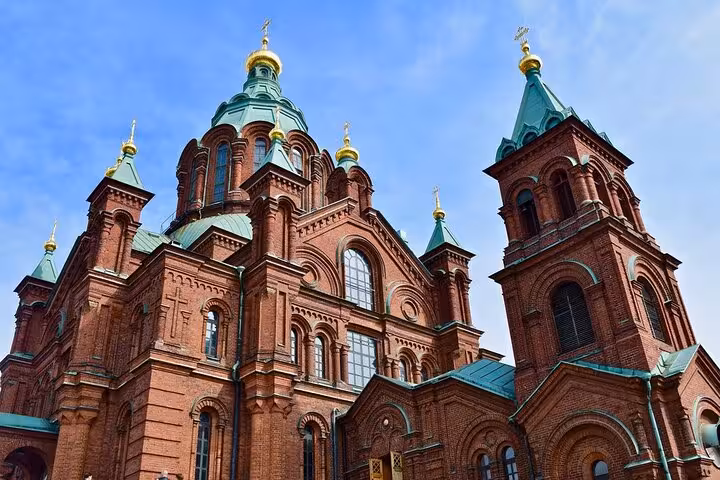 Stunning red-brick cathedral with green domes and gold accents, a highlight on the Helsinki walking tour.