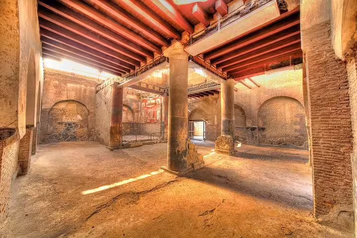 Herculaneum ruins interior with ancient columns and frescoed walls on low-cost day trip from Naples