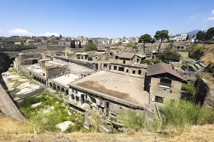 Wide-angle shot of Herculaneum ruins and terraced buildings seen on a personalized guided tour from Naples with Mount Vesuvius nearby