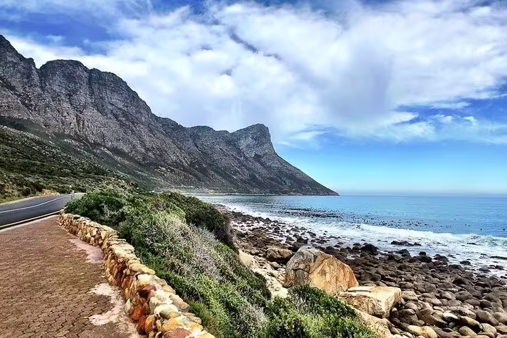 Scenic coastal road with mountain and ocean views along the route to Hermanus, South Africa.