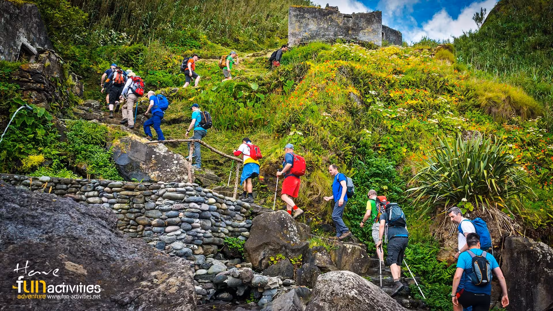 Group hiking stone steps through lush Ribeira Funda valley toward Maia, São Miguel guided trek experience