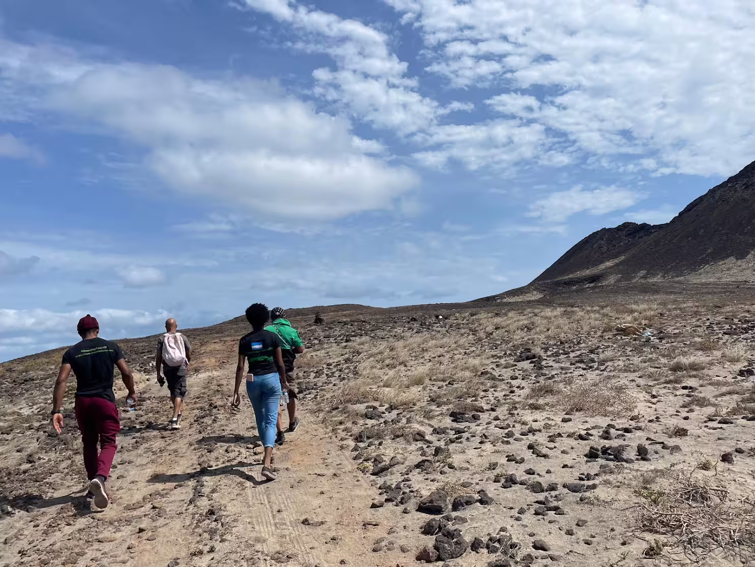 Hikers explore the rugged terrain under a blue sky on the Volcano Viana trail in São Vicente, Cape Verde, embracing adventure.