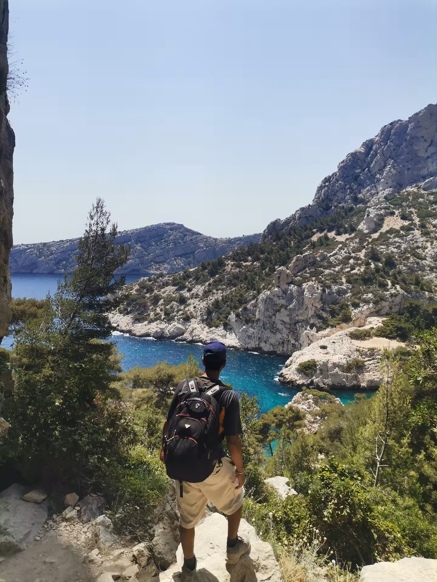 Hiker overlooks turquoise Calanques cove on Provence coastal trail during a 14-day hiking and culture journey