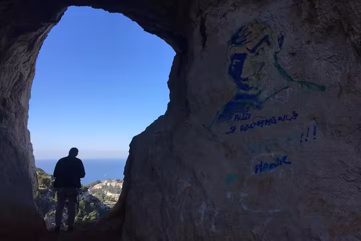 Hiker in a sea-view cave on Les Calanques trail, panoramic Marseille hike with Mediterranean vista
