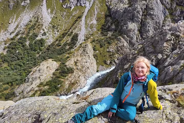 Hiker resting on rocky alpine trail above rushing stream near Trift Suspension Bridge on Zurich day trip