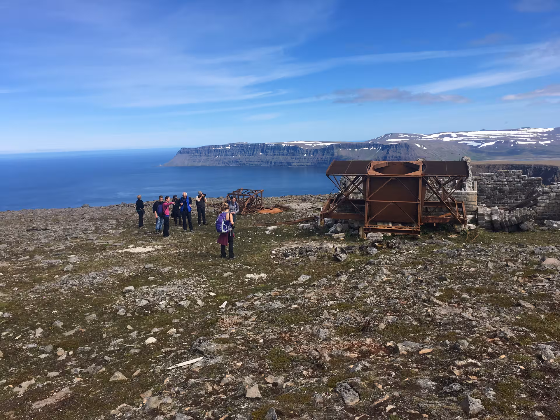 Hikers on Arctic coastal plateau beside historic ruins, scenic viewpoint for Solar Eclipse Hike adventure