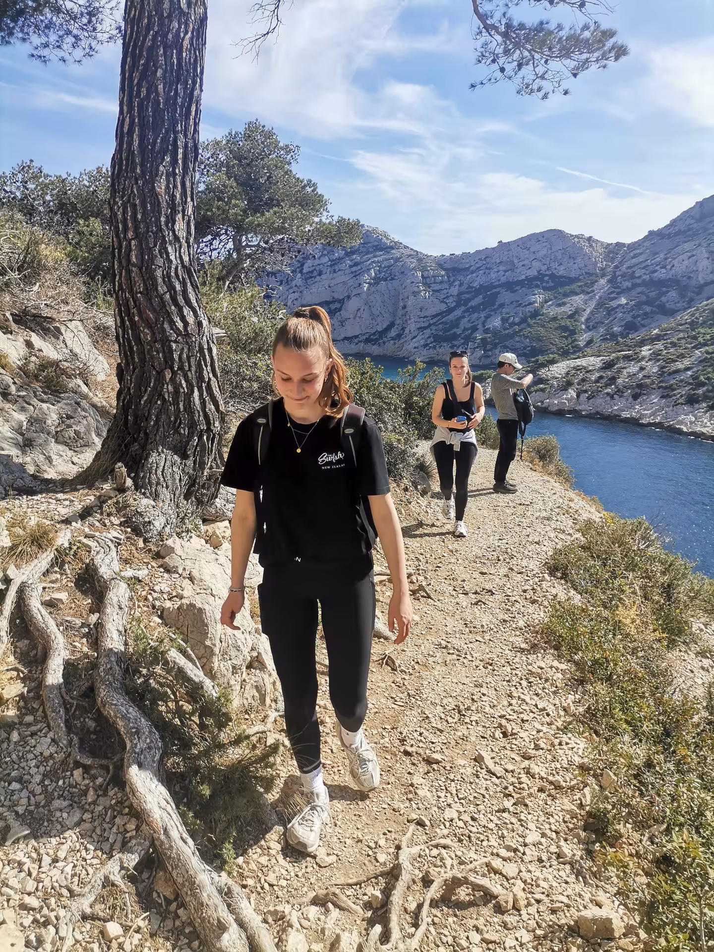 Hikers on a coastal trail in the Calanques of Provence, with limestone peaks and blue sea views near Marseille