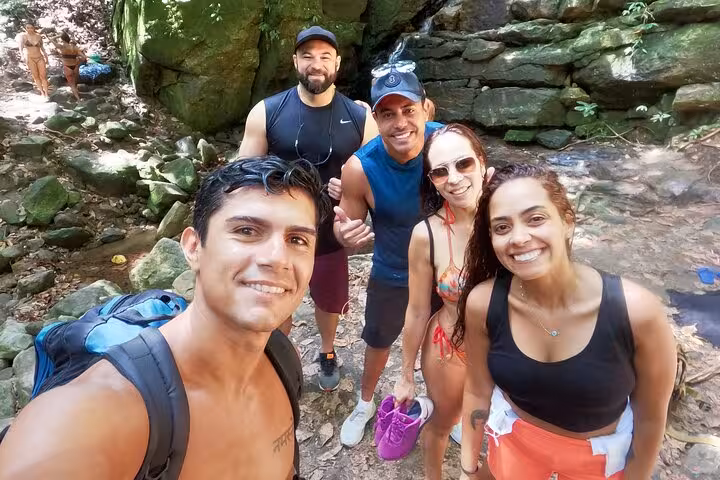 Group of hikers smiling by a rocky path on the Garganta do Céu and Waterfall hike in Pedra da Gávea.