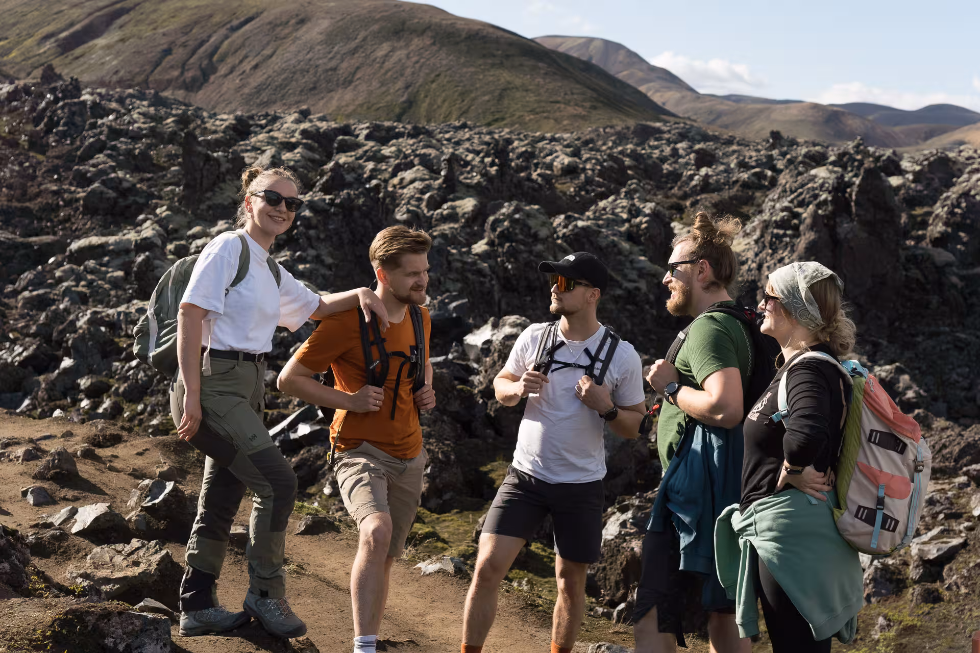 Group of hikers resting on lava field in Landmannalaugar, Iceland Highlands, on guided trekking day tour