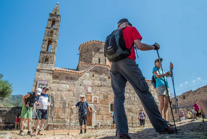 Hikers with trekking poles at historic stone church in Kardamyli, Mani Peninsula, Greece guided walking tour