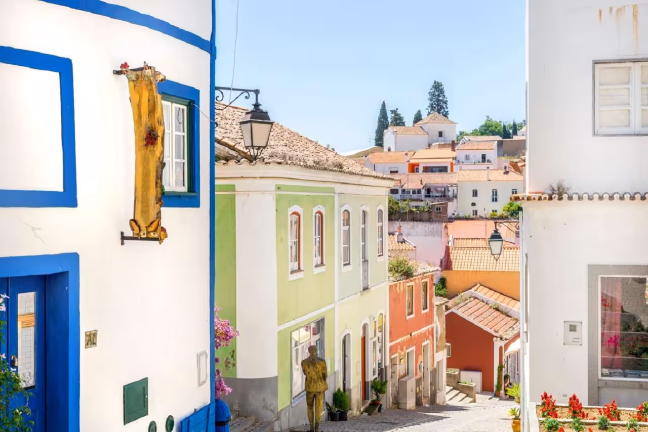 Colorful historic houses on a steep cobbled street in a traditional Algarve village, perfect stop on a full day guided tour