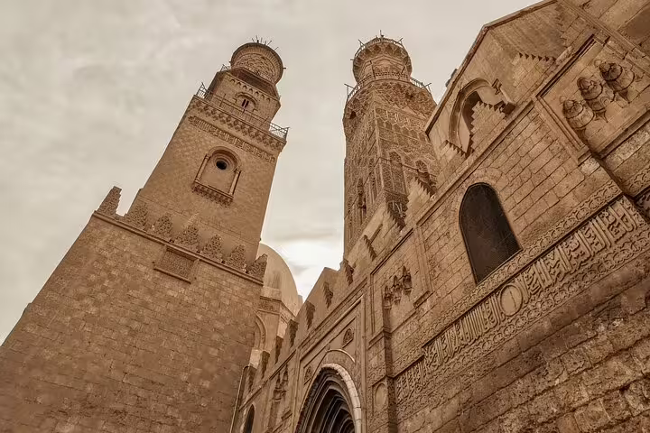 Historic Cairo mosque facade with twin minarets and carved stonework, Islamic architecture tour in Egypt