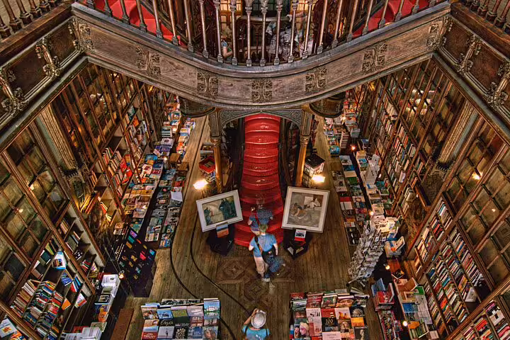 Aerial view of historic bookstore interior with ornate wooden balconies and red staircase, featured in private tuk tuk tour.