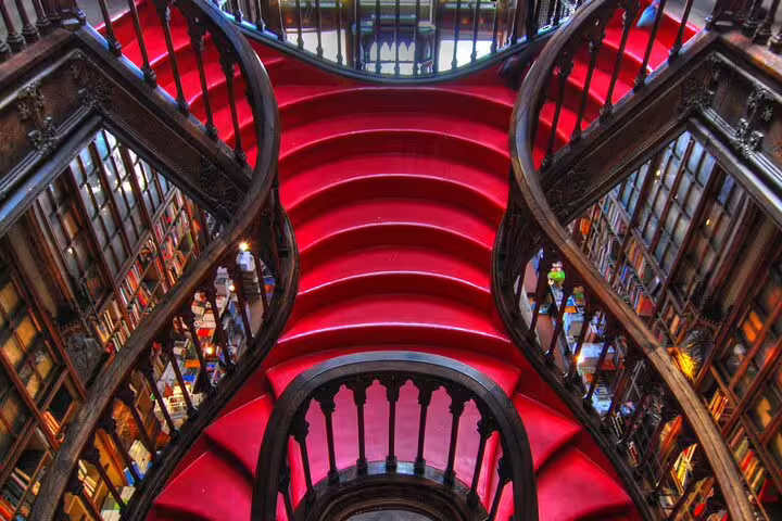 Vibrant red staircase in a historic library, showcasing ornate woodwork and a unique architectural design, perfect for cultural tuk tuk tours.