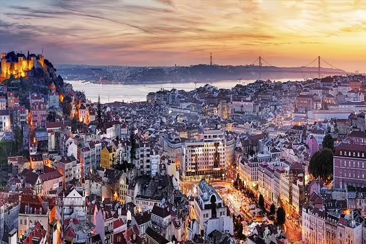 Aerial view of historic Lisbon at sunset, showcasing vibrant architecture, the Tagus River, and iconic landmarks for a half-day tour.