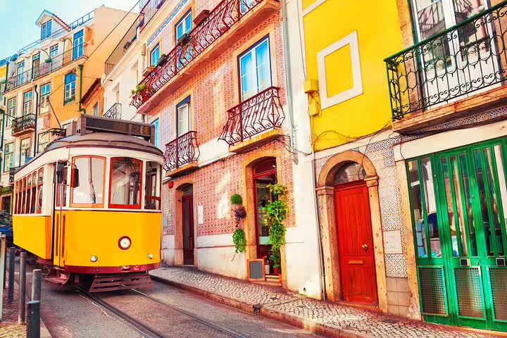 Historic Lisbon tram passing colorful tiled buildings in Alfama district, capturing the essence of Portuguese culture and fado music.
