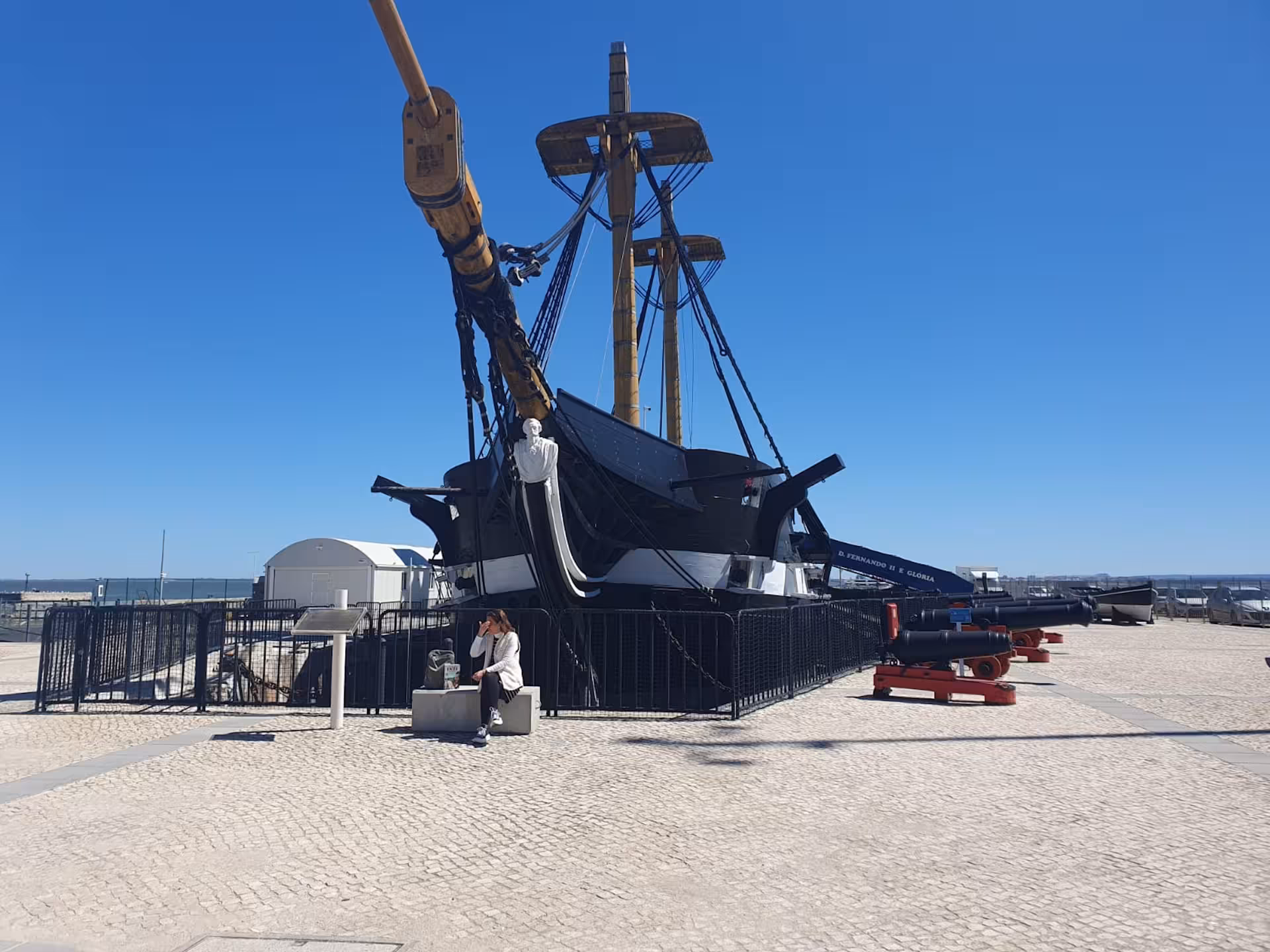 Historic ship at Almada's dock under a clear blue sky, showcasing maritime heritage near Lisbon.
