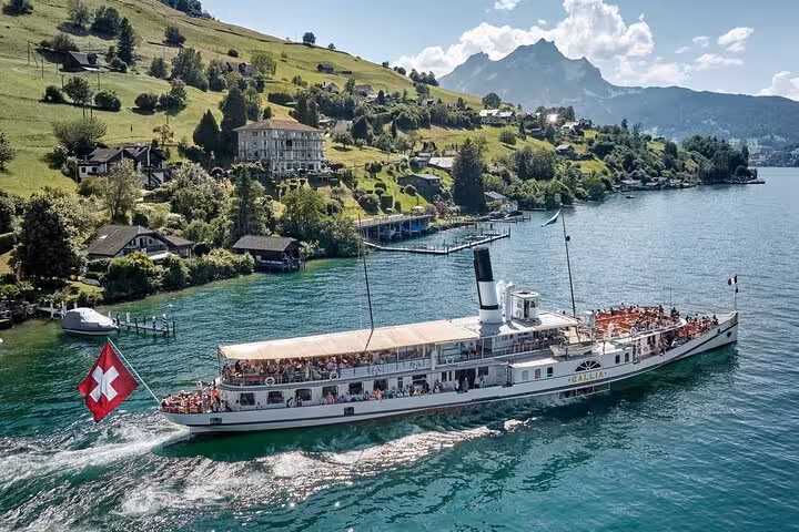 Historic steamship cruising on Lake Lucerne with picturesque Swiss countryside and Alps in the backdrop.