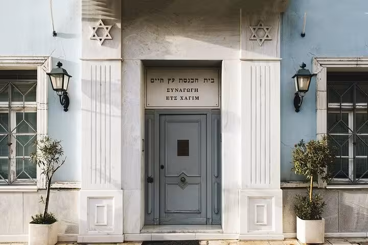 Entrance of a historic synagogue in Athens, featuring Hebrew inscriptions and Star of David symbols.