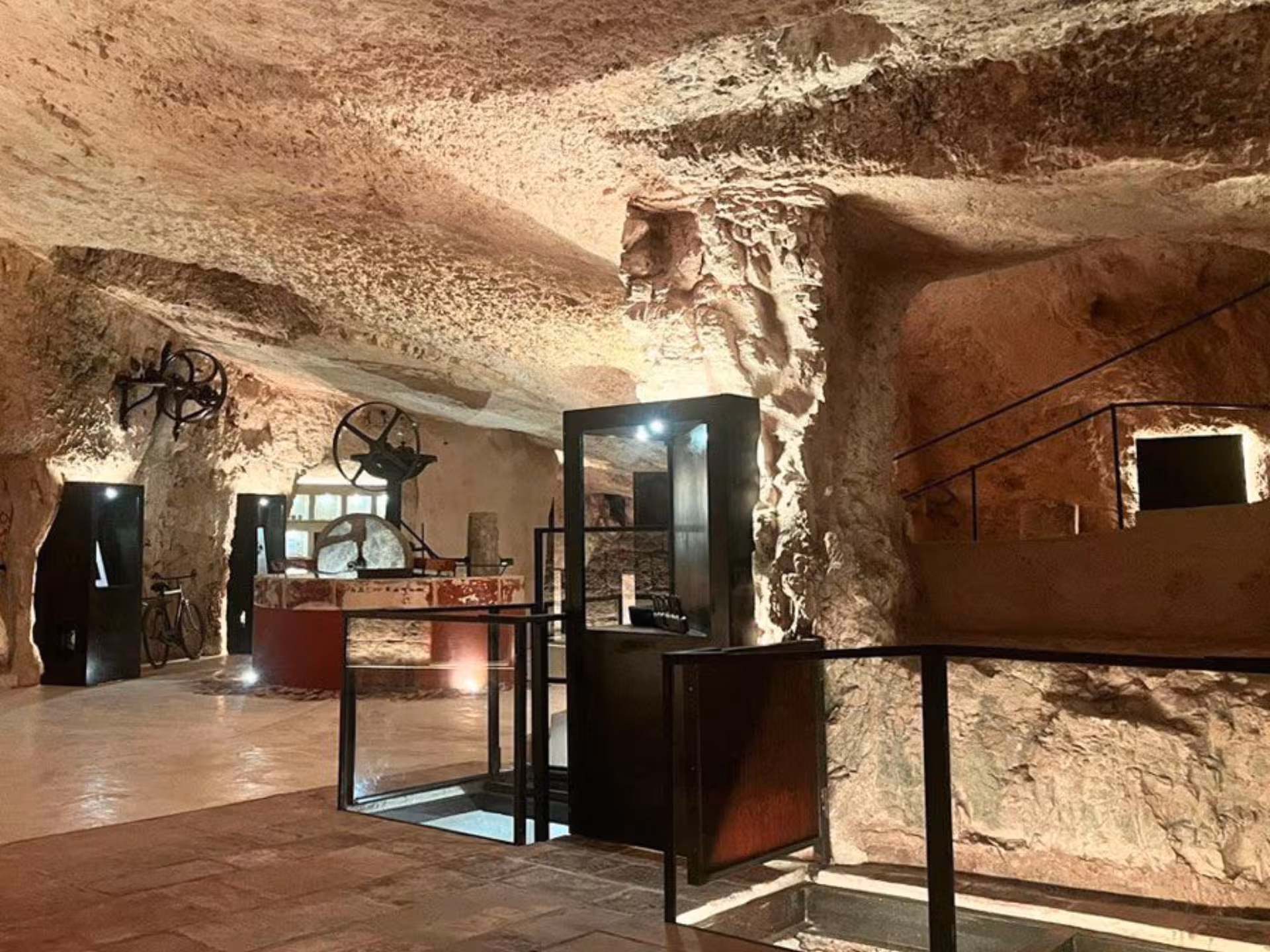 Interior of a historic underground mill showcasing milling equipment and stone walls in a rustic setting near Ostuni.