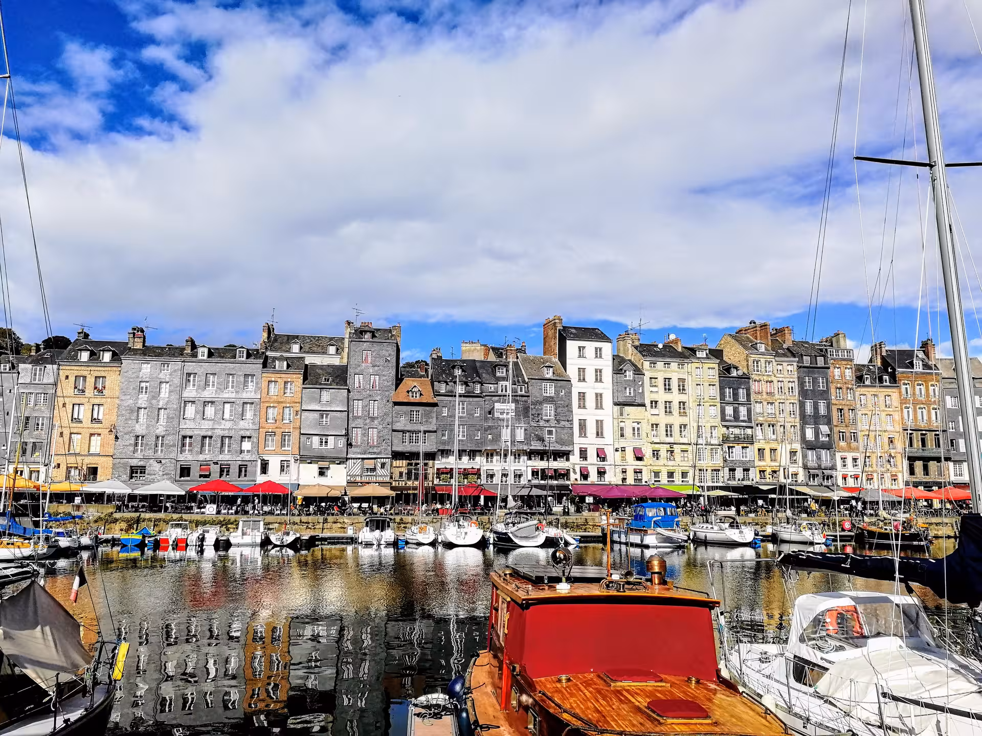 Honfleur Vieux Bassin harbor views on guided electric bike tour, with sailboats and colorful waterfront buildings