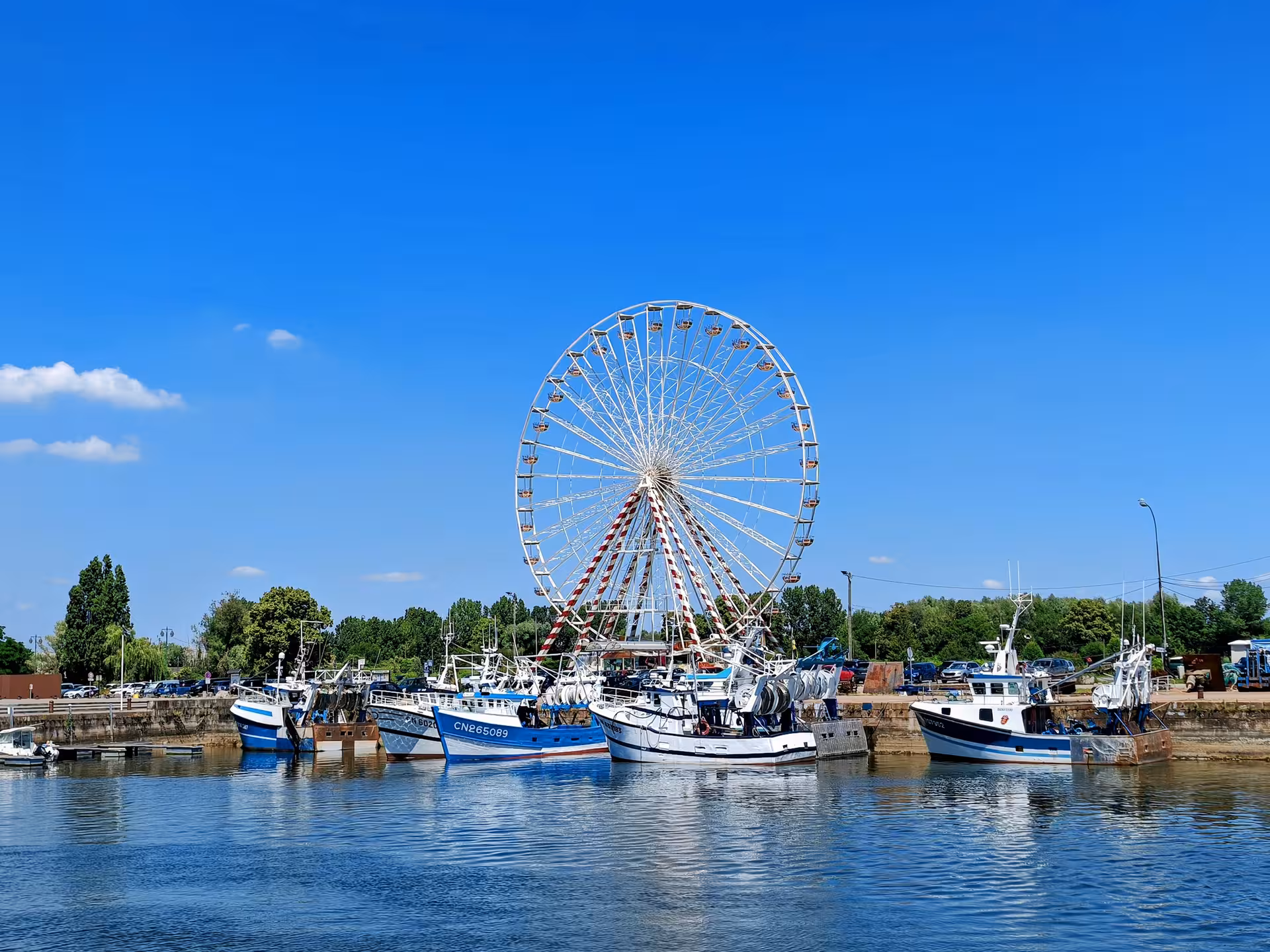 Honfleur harbor with fishing boats and Ferris wheel, scenic stop on guided electric bike tour along the waterfront