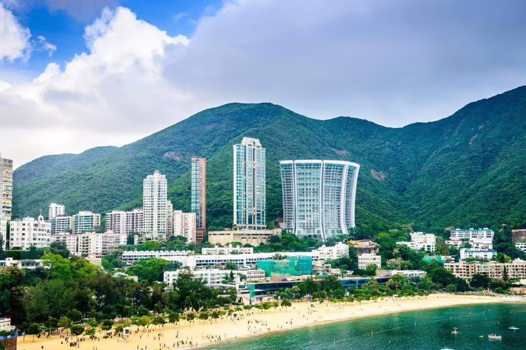 Repulse Bay beach with lush green mountains and modern skyscrapers, ideal for a Hong Kong private city tour.