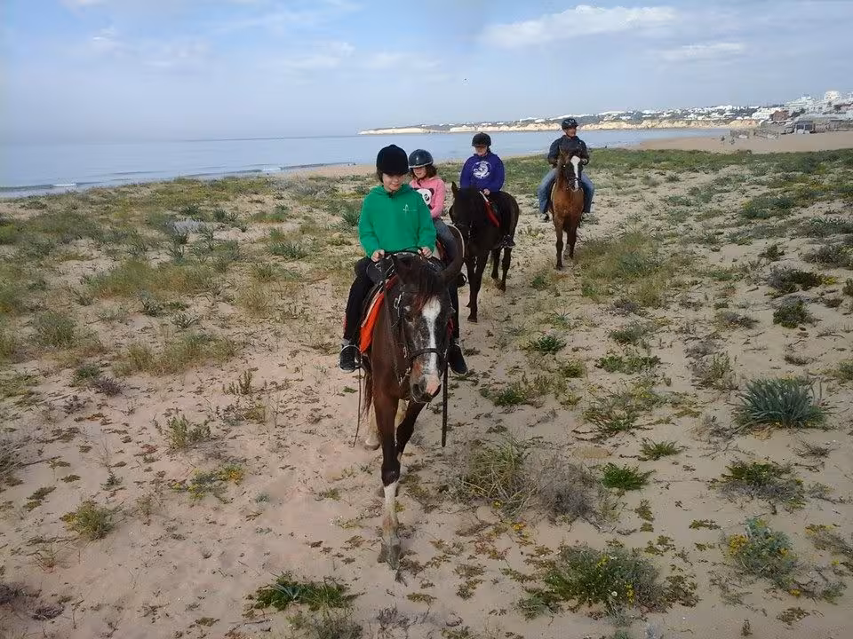 Group of riders on horses enjoying a scenic beach trail at Lagoa Dos Salgados in the Algarve.