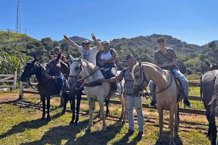 Smiling group of horseback riders enjoying a sunny day in Brazil's scenic Atlantic Forest.