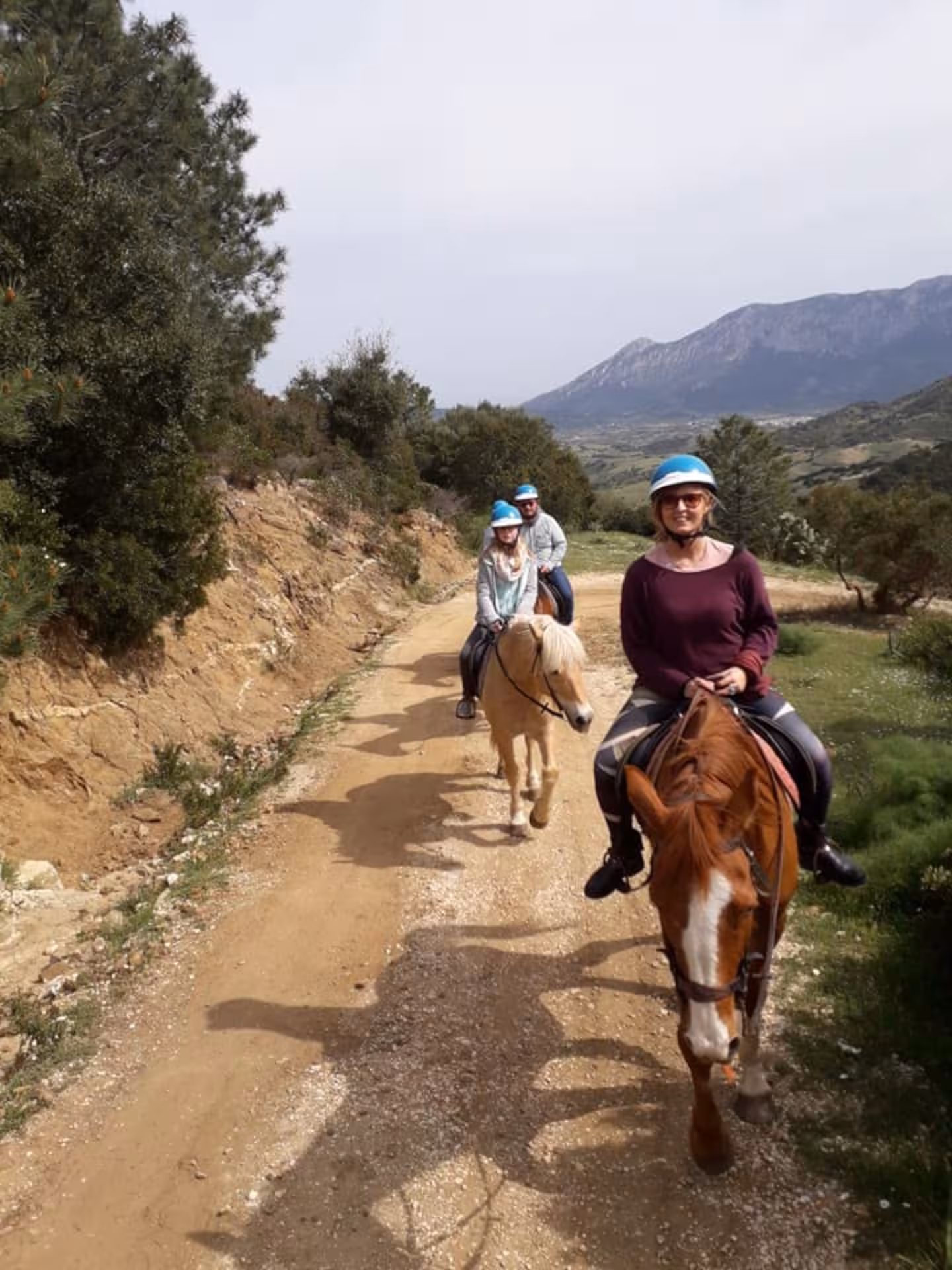 Group enjoying scenic horseback riding tour in Irgoli, Sardinia, with stunning mountain views in the background.
