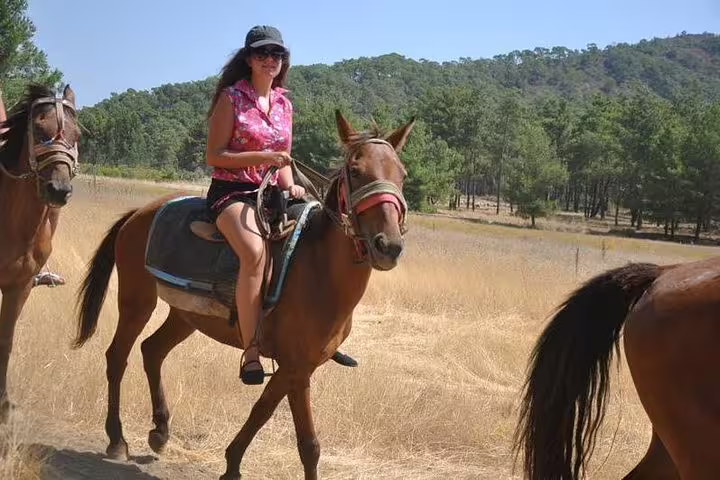 Cruise guest enjoying horseback riding through scenic trails near Kusadasi Port, surrounded by lush greenery.