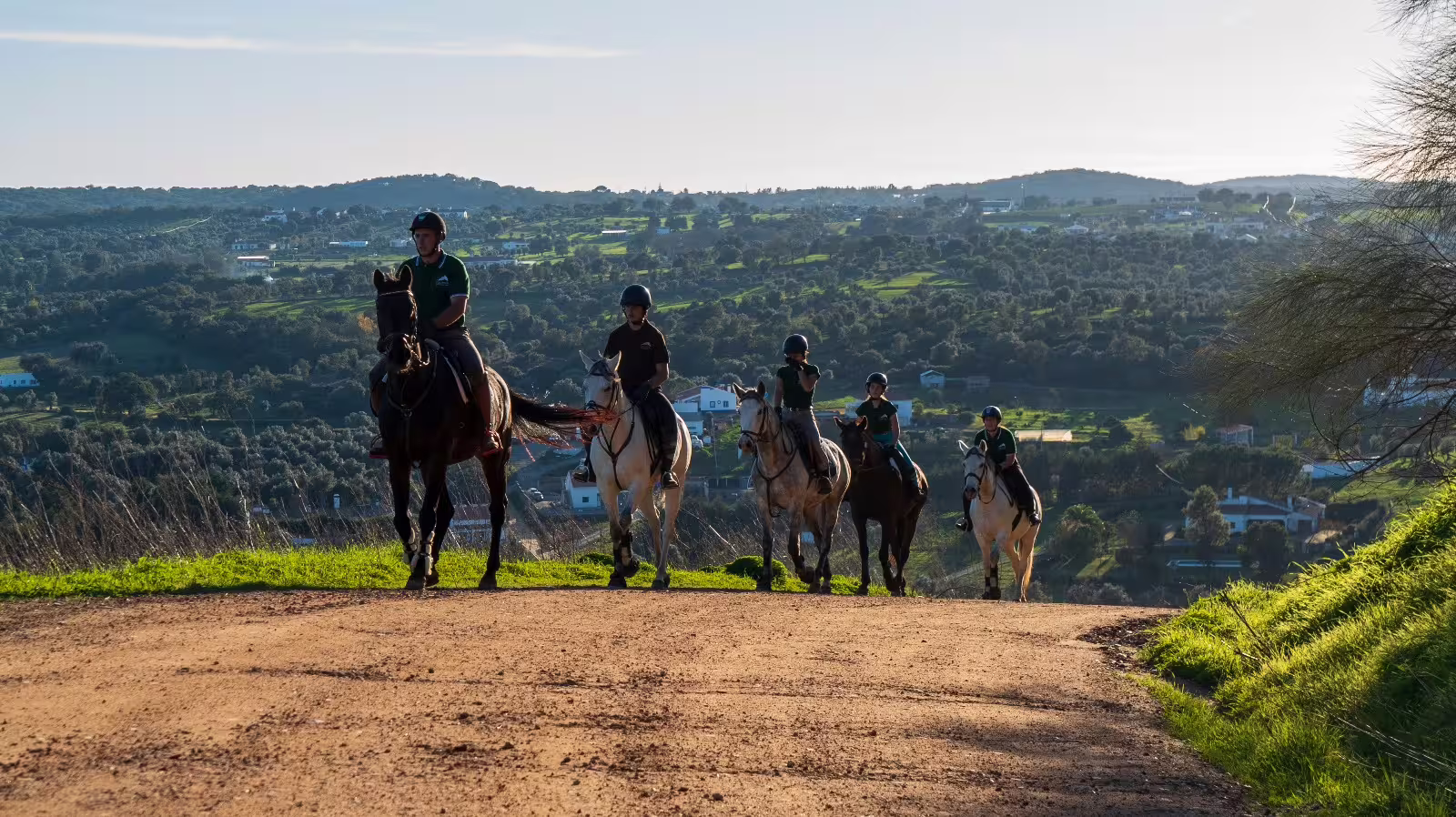 Horseback riders overlooking a panoramic view of the montado landscape with rolling hills.