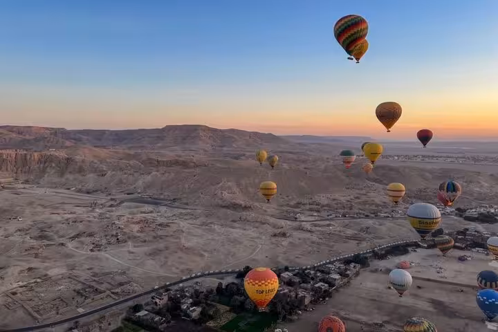 Sunrise hot air balloons over Luxor West Bank desert on a Luxor balloon ride with hotel pickup and drop-off