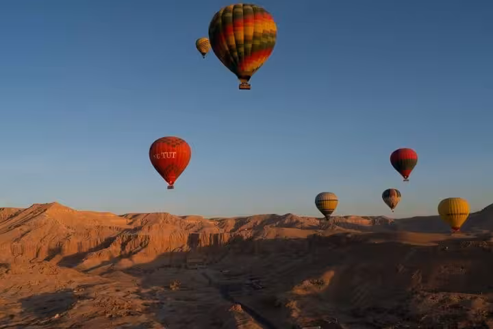 Hot air balloons floating over Luxor desert at sunrise, Egypt, scenic balloon ride with hotel pickup and drop-off