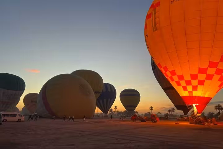 Hot air balloons inflating at Luxor launch site at sunrise, pre-flight view on West Bank tour with pickup