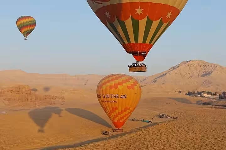 Hot air balloons floating over Luxor desert at sunrise, scenic balloon ride tour with hotel pickup and drop-off
