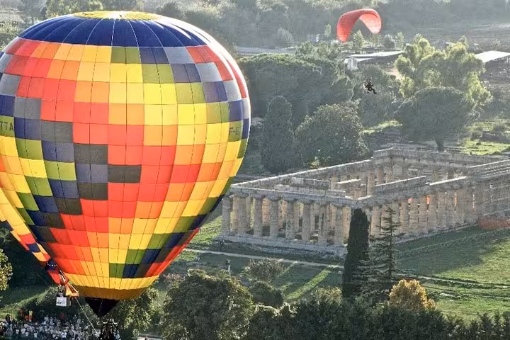 Colorful hot air balloon soaring over the historic Paestum temples, offering a unique perspective on the private tour from Sorrento.