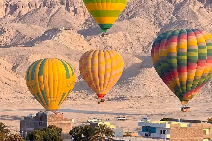 Hot air balloons floating over Luxor desert mountains at sunrise on a scenic balloon ride with hotel pickup